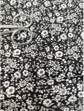 Tela de algodón estampado flores blancas fondo negro.