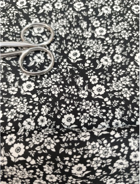 Tela de algodón estampado flores blancas fondo negro.