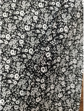 Tela de algodón estampado flores blancas fondo negro.